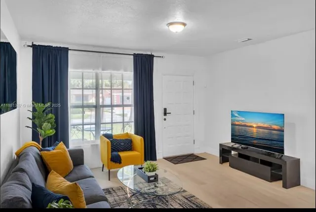 a living room with furniture a flat screen tv and a window