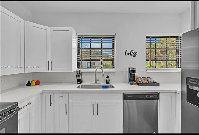 a kitchen with white cabinets and sink