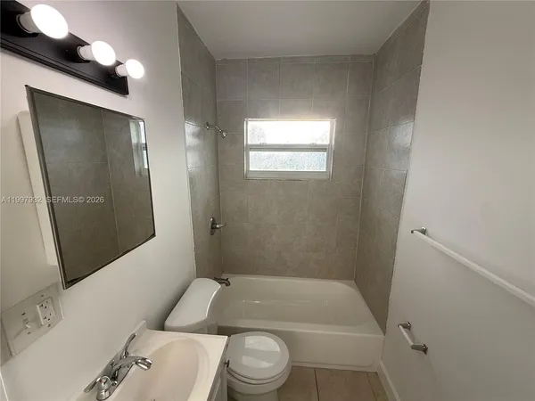 a bathroom with a granite countertop bathtub shower sink vanity and toilet