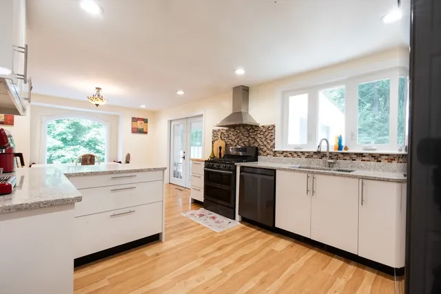 an empty room with windows chandeliers and kitchen view