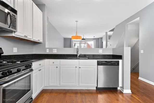 a kitchen with granite countertop white cabinets and stainless steel appliances