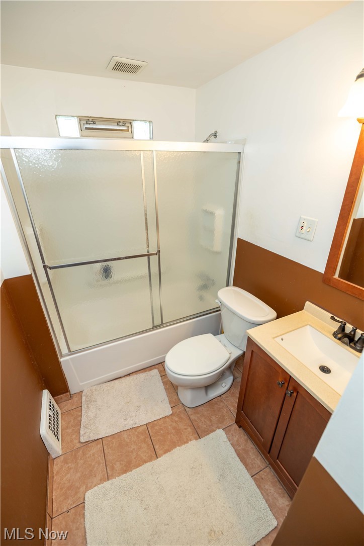 10105 Unity Avenue Cleveland, OH 44111 - Photo 16 of 35 Full bathroom featuring toilet, tile flooring, shower / bath combination with glass door, and vanity with extensive cabinet space