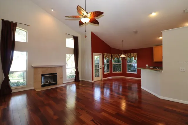 an empty room with wooden floor a chandelier fan and a fireplace