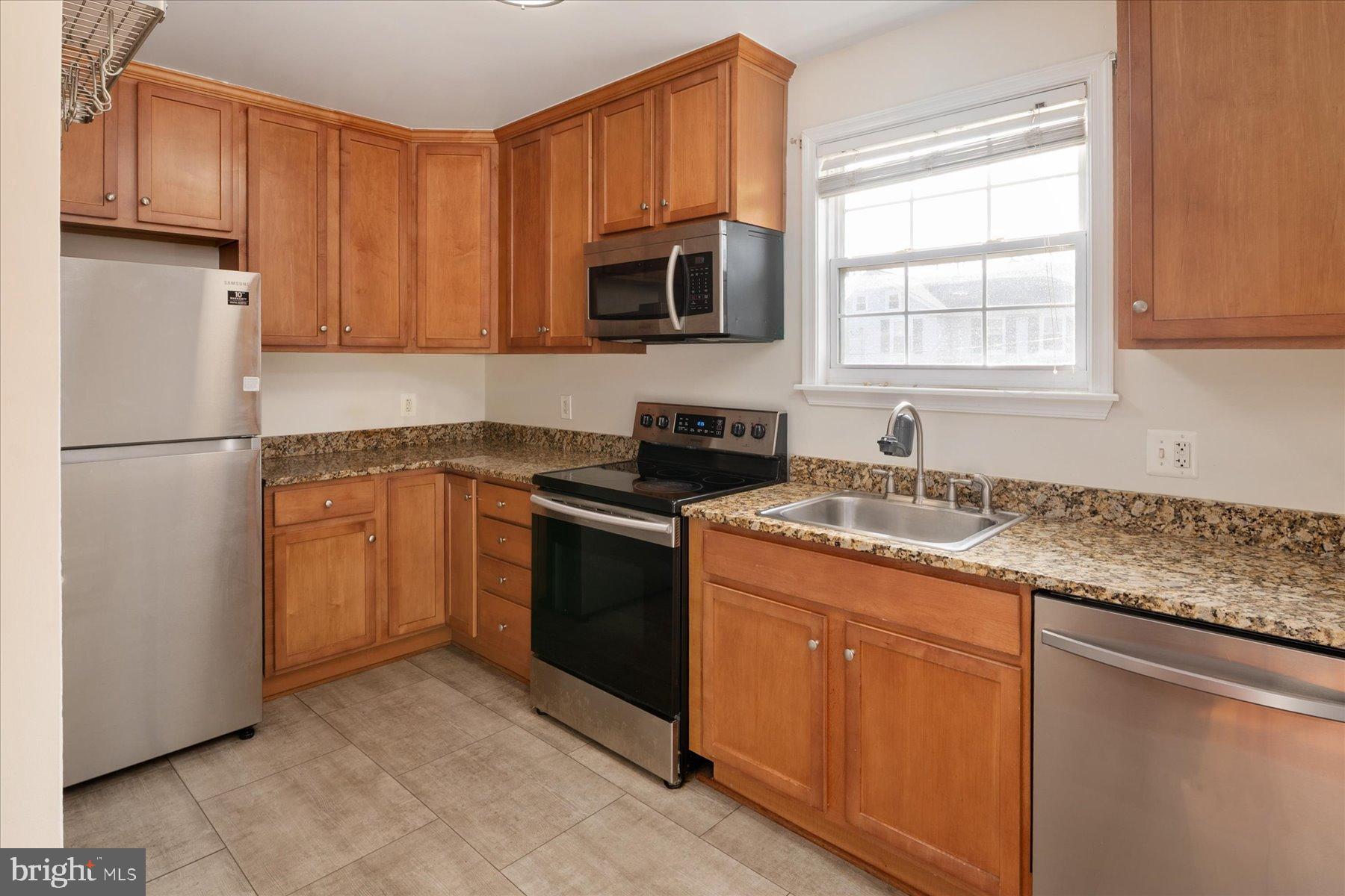 19 Post, Unit AVENUE 203 Laurel, MD 20707 - Photo 13 of 32 a kitchen with granite countertop stainless steel appliances a refrigerator sink and microwave