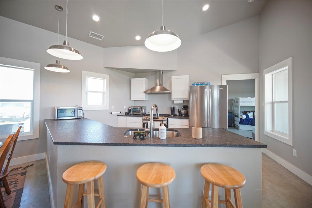 131.7-acres Roney Road Jacksboro, TX 76458 - Photo 7 of 40 a kitchen with stainless steel appliances granite countertop a stove a refrigerator a sink dishwasher a dining table and chairs with wooden floor