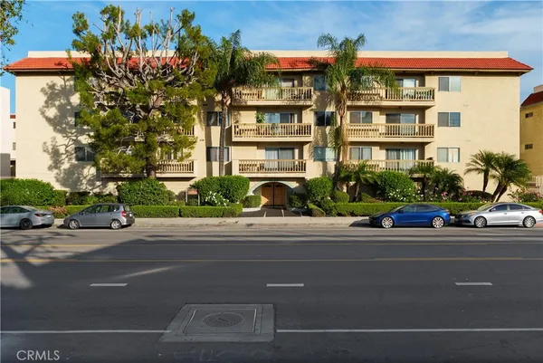 a front view of multi story residential apartment building with yard and parking