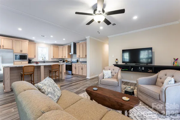 a living room with furniture and a flat screen tv with kitchen view