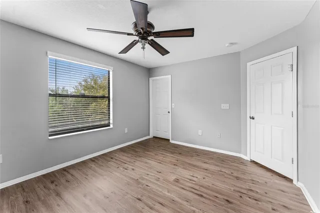 a view of an empty room with a window and wooden floor