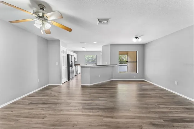 a view of an empty room with window and wooden floor