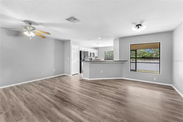 a view of a kitchen with furniture a ceiling fan and wooden floor
