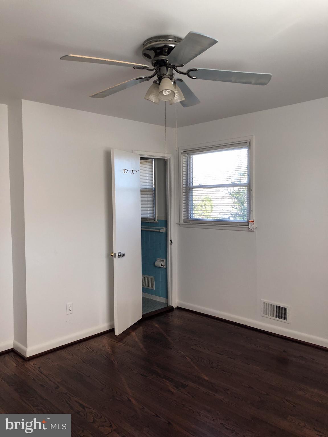10005 Riggs Road Adelphi, MD 20783 - Photo 10 of 32 a view of an empty room with wooden floor and a ceiling fan