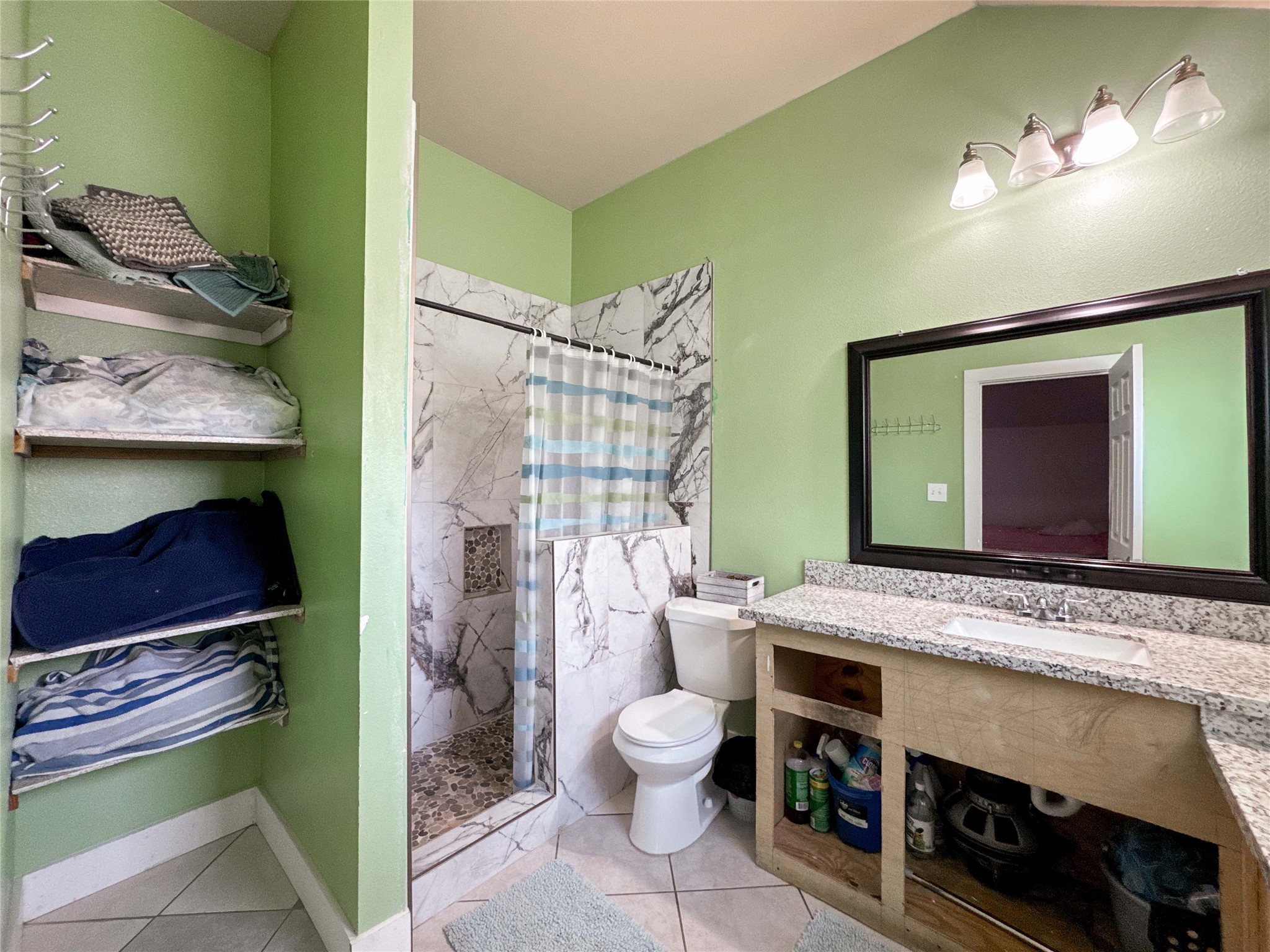 1060 County Road 5021 Cleveland, TX 77327 - Photo 19 of 34 a bathroom with a granite countertop sink a toilet and shower