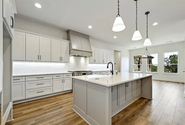 a kitchen with a sink stove and wooden floor