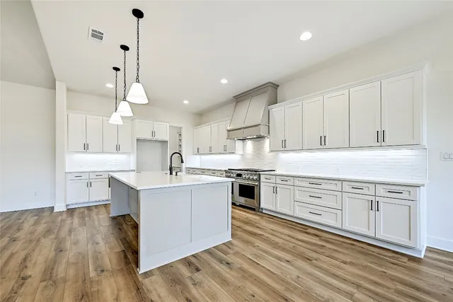 a large kitchen with cabinets wooden floor and stainless steel appliances