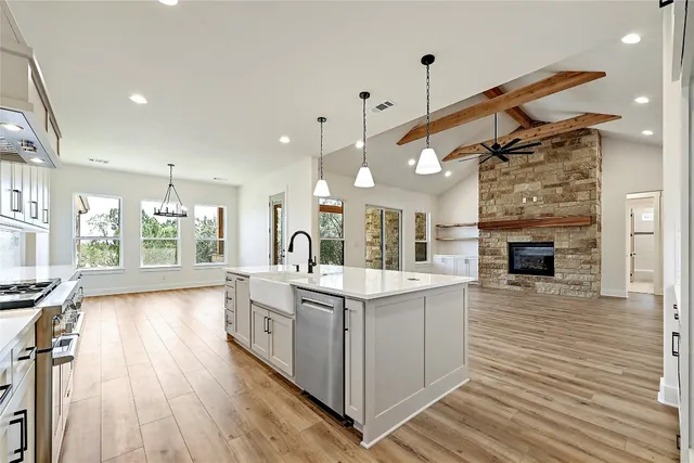 a large white kitchen with a large window a sink and stainless steel appliances