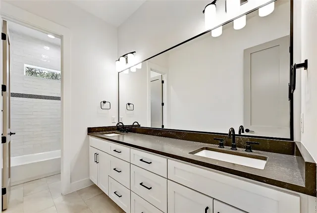 a bathroom with a double vanity sink and mirror with bathtub