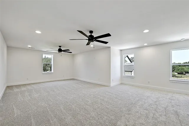 an empty room with windows and ceiling fan