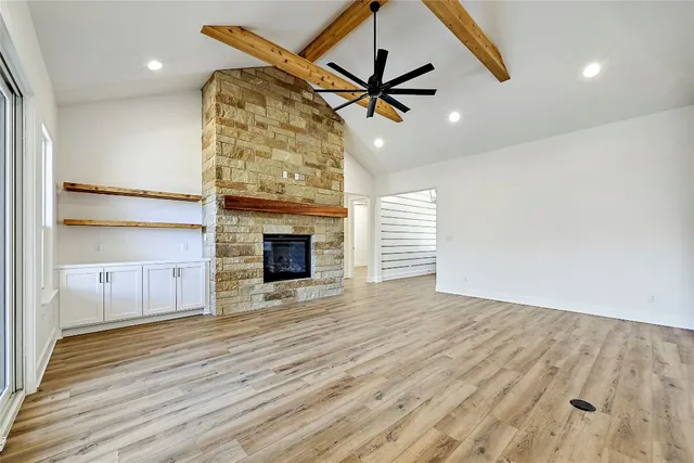 a view of a livingroom with wooden floor a ceiling fan and windows