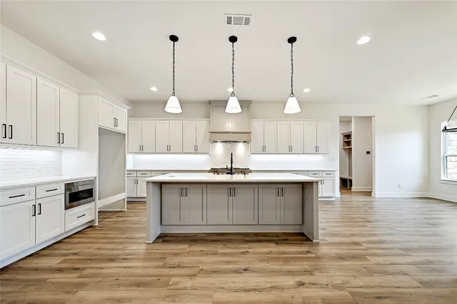a kitchen with kitchen island a stove a sink and a wooden floor