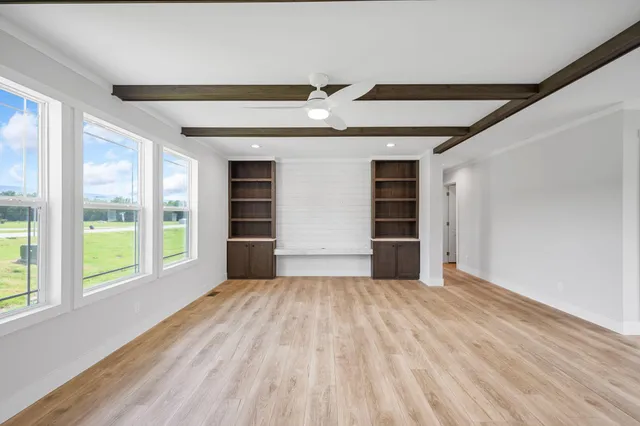 a view of an empty room with a window and wooden floor
