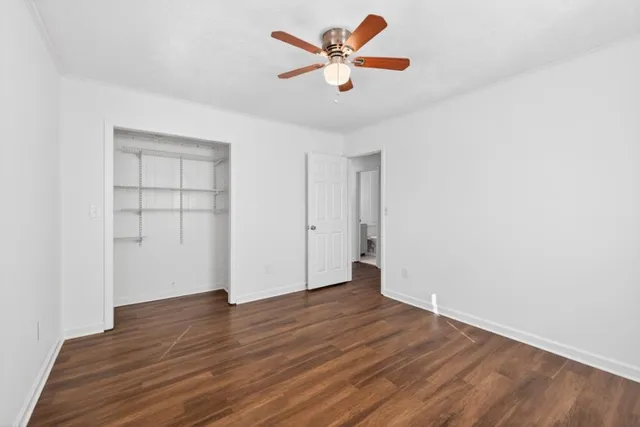 an empty room with wooden floor and a ceiling fan