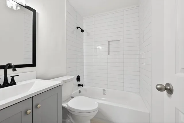a bathroom with a bathtub shower sink vanity mirror and toilet