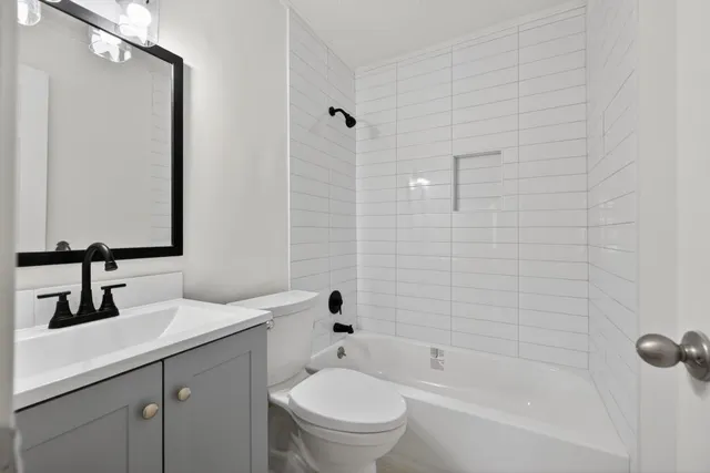 a bathroom with a bathtub shower sink mirror and toilet