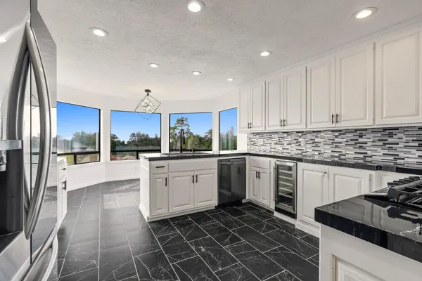 a kitchen with granite countertop white cabinets and stainless steel appliances