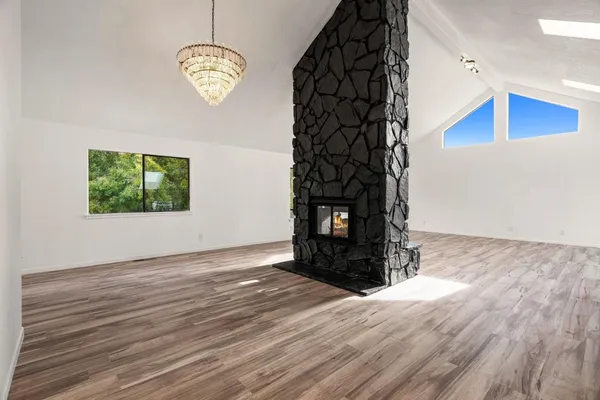 an empty room with wooden floor fan and windows