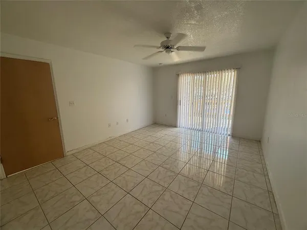 an empty room with a ceiling fan and window