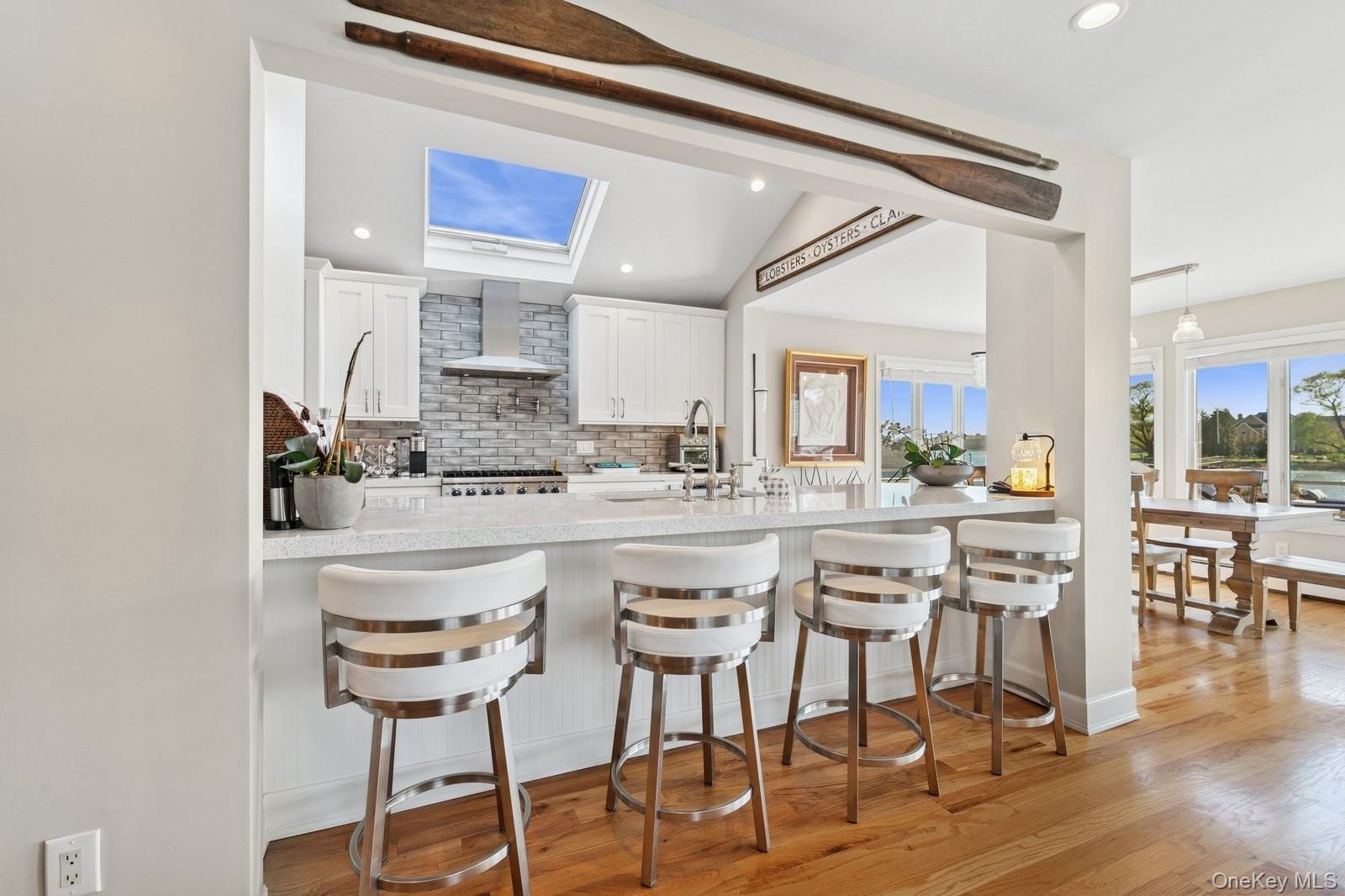 81 Beach Road Aquebogue, NY 11901 - Photo 22 of 34 a kitchen with a dining table chairs cabinets and stainless steel appliances