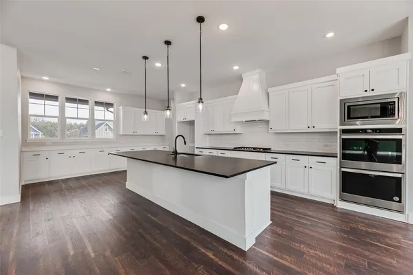 a kitchen with stainless steel appliances granite countertop a sink a stove and a wooden floors