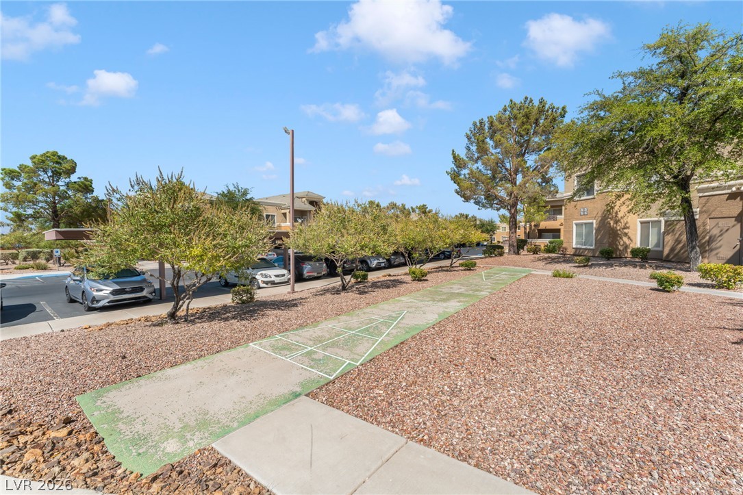 8070 West Russell Road, Unit 1054 Las Vegas, NV 89113 - Photo 22 of 22 A community shuffleboard court awaits, nestled among vibrant green trees and apartment buildings.