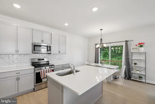 a kitchen that has a lot of cabinets in it with stainless steel appliances granite countertop a stove and a sink