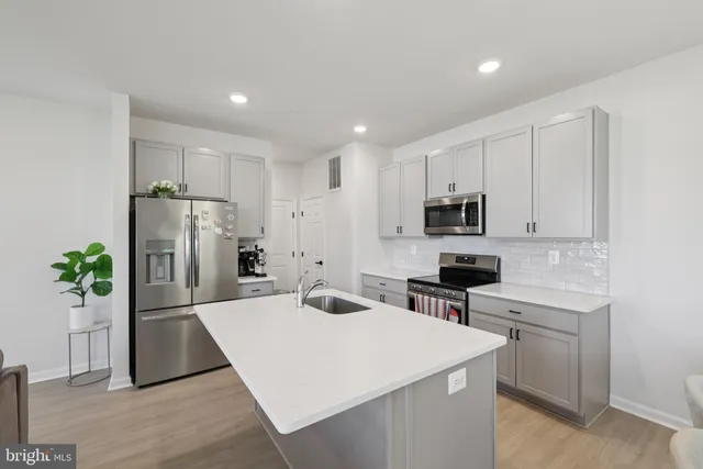 a kitchen with a refrigerator a stove top oven a sink and cabinets