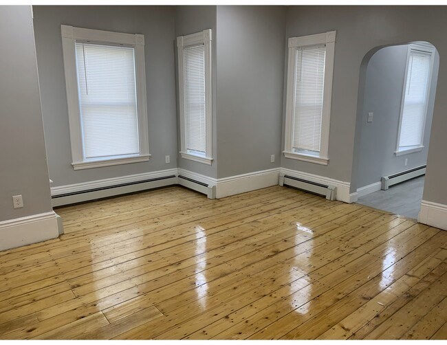 153 Chestnut Street, Unit 1 Waltham, MA 02453 - Photo 3 of 10 a view of an empty room with wooden floor and a window