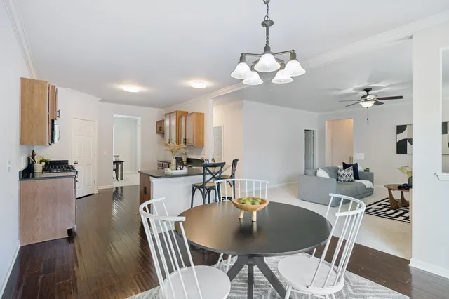 a kitchen with granite countertop a sink a stove and chairs with wooden floor
