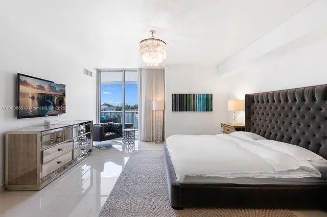 a large bedroom with a bed and flat tv screen on dresser