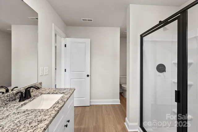 a bathroom with a granite countertop sink a mirror and shower