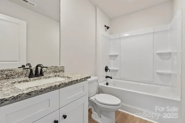 a bathroom with a granite countertop sink toilet mirror and bathtub
