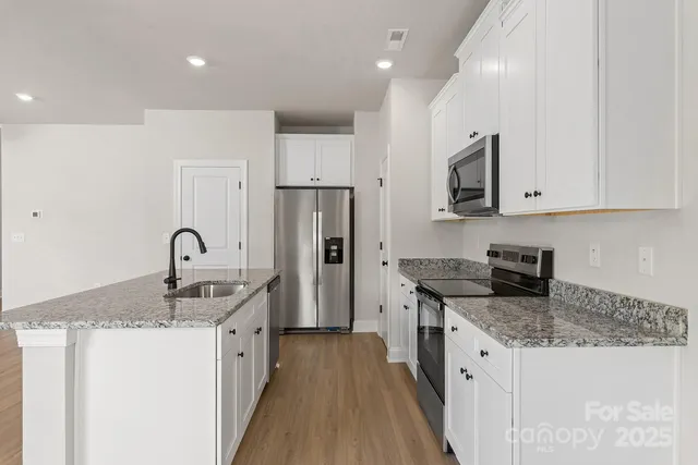 a kitchen with granite countertop a sink stove and refrigerator
