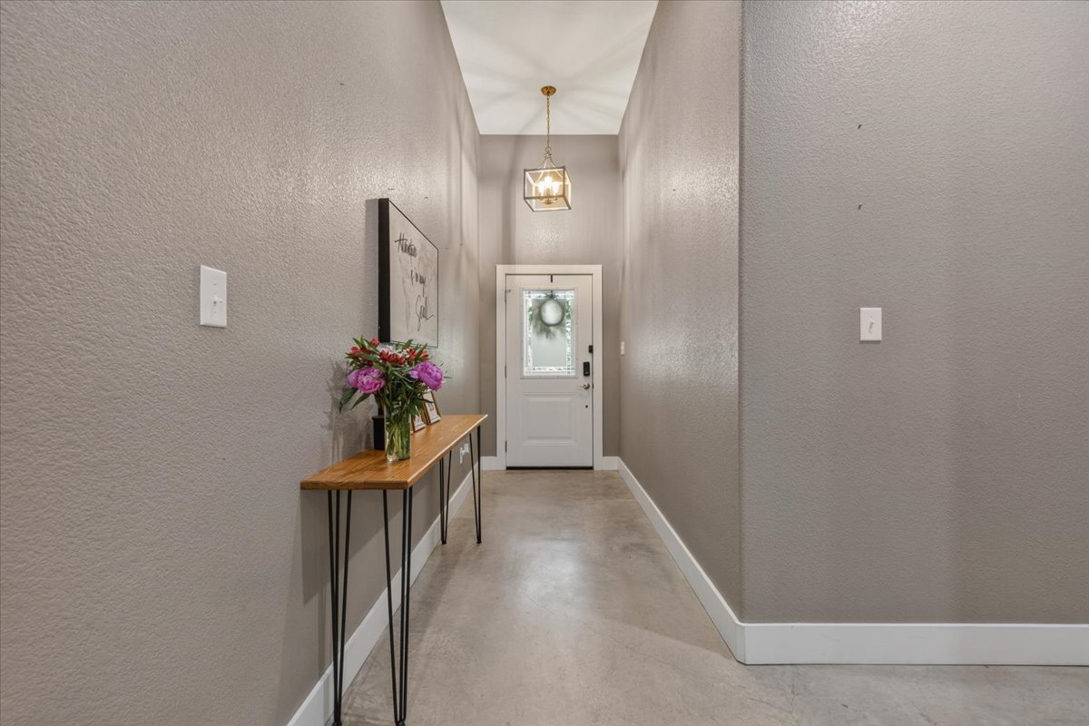 145 Cardinal Loop Paige, TX 78659 - Photo 6 of 40 A welcoming entryway with sleek concrete flooring and a modern pendant light.