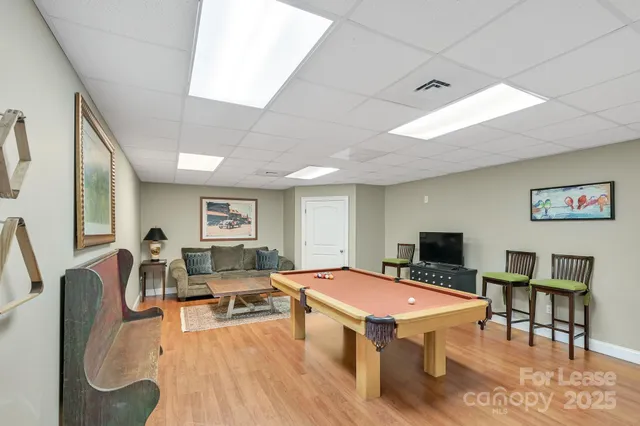 a room with furniture pool table wooden floor and a flat screen tv