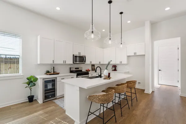 a kitchen with stainless steel appliances kitchen island a stove a sink a refrigerator a stove a dining table and chairs with wooden floor