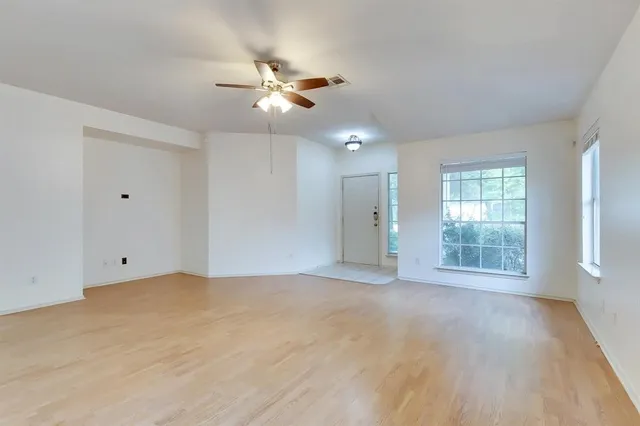 a view of an empty room with a window and wooden floor