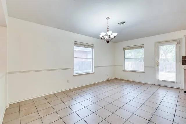 an empty room with chandelier fan and window