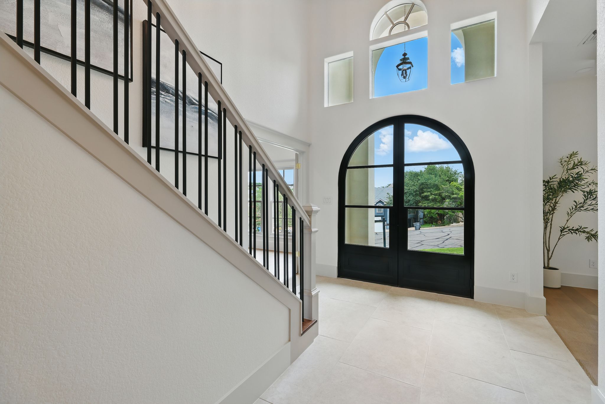 6905 Rudi Cove Austin, TX 78759 - Photo 3 of 36 Step into a grand foyer, where a towering ceiling draws the eye upward, complementing the elegant travertine tile flooring and a uniquely crafted staircase. A custom-designed Durango door sets the tone for this exceptional residence.