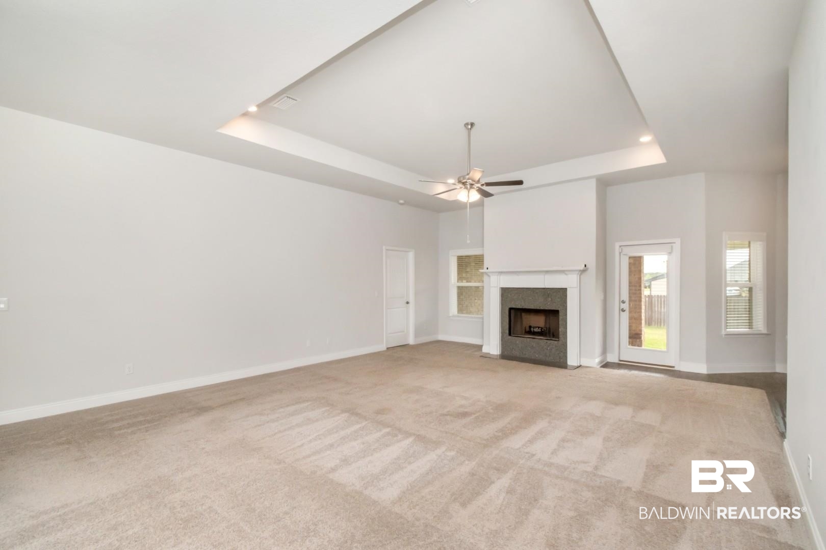 6632 Monarch Circle Mobile, AL 36618 - Photo 5 of 32 Unfurnished living room with light carpet, a high end fireplace, a ceiling fan, and a raised ceiling