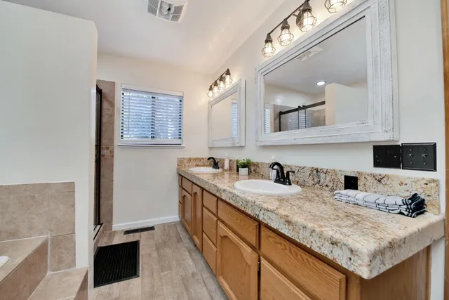 a bathroom with a toilet sink vanity granite and shower