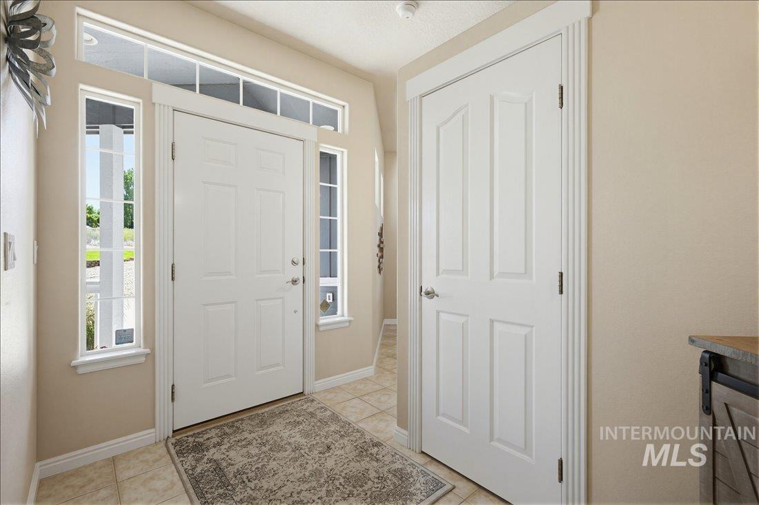 24623 Falcon Lane Caldwell, ID 83607 - Photo 5 of 40 Entryway featuring a white paneled door with sidelights, transom windows, and tile flooring